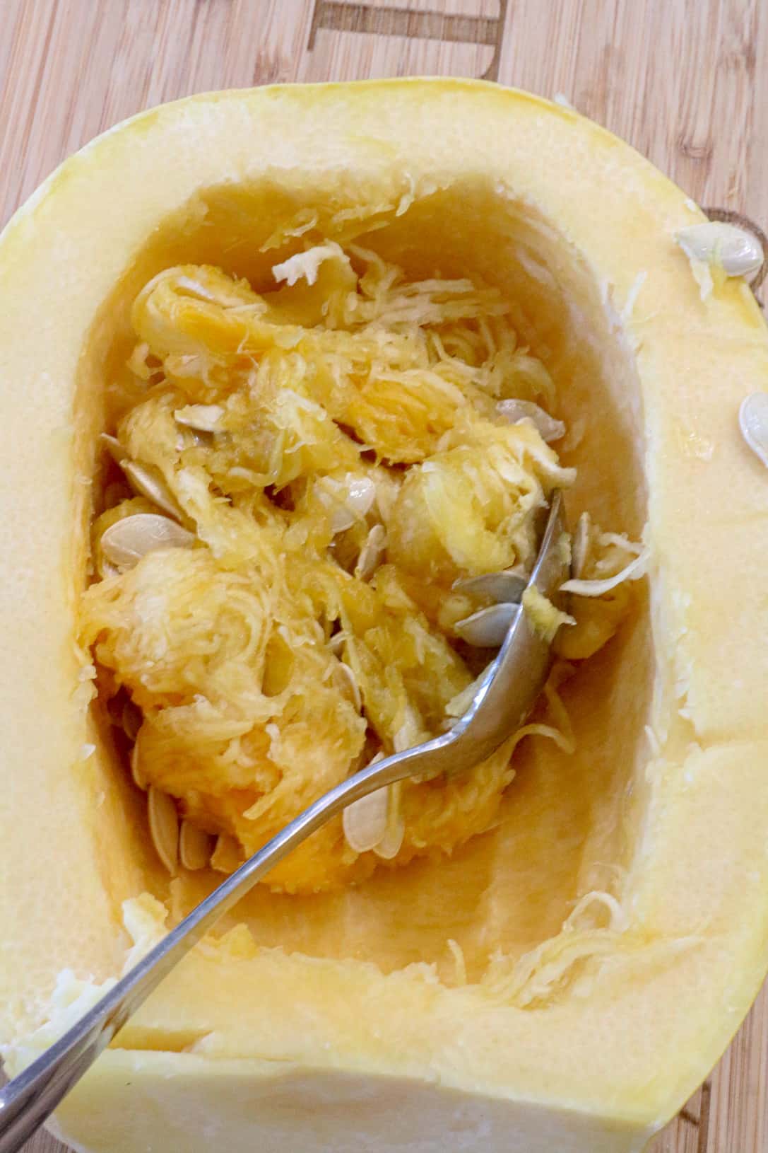 spoon scraping seeds out of squash