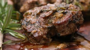 Baked lamb chops on wooden board topped with rosemary