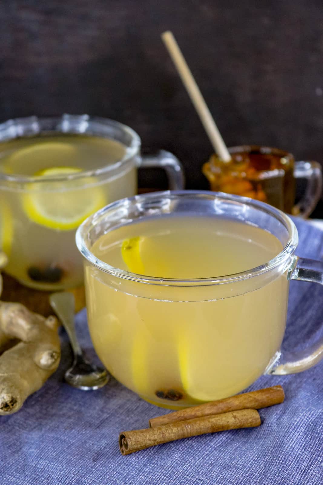 Ginger Tea Recipe With Lemon In clear glass with cinnamon sticks on the side