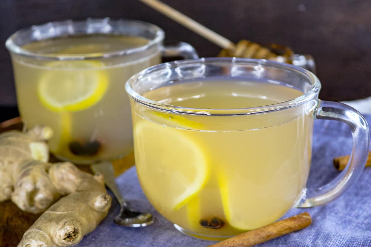 Ginger tea in clear mug with ginger cinnamon and ginger on the side