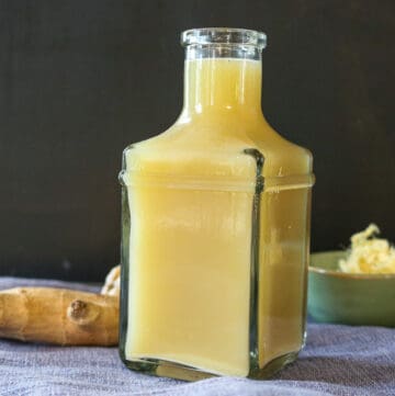 quick and easy ginger juice without a juicer. ginger tea in clear bottle with ginger in the background