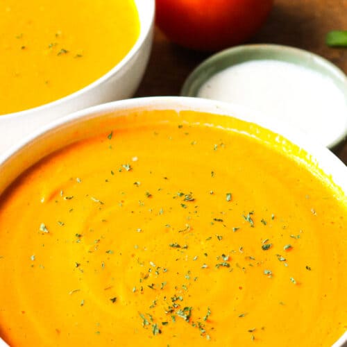 soup in white bowls topped with herbs