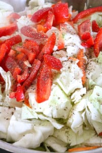 cabbage topped with red bell peppers and seasoning