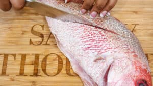 slicing fish on both sides on cutting board