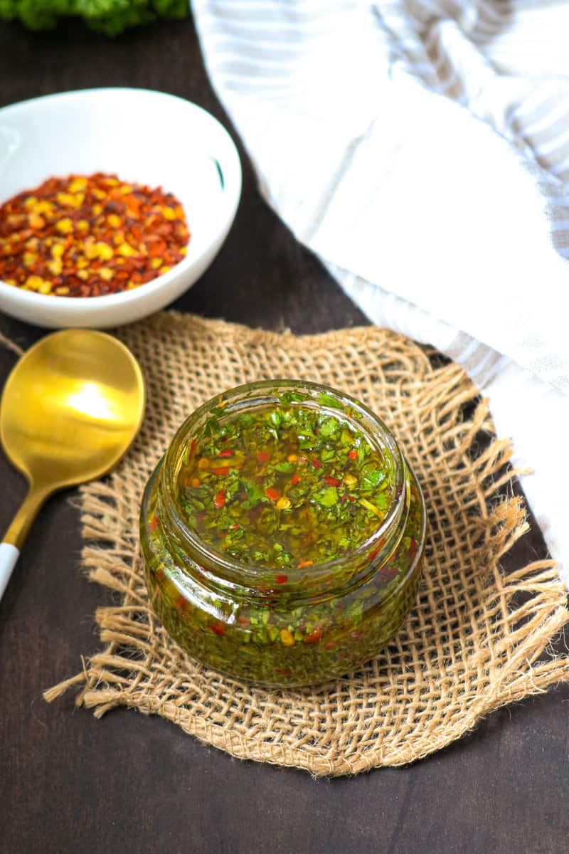CHIMICHURRI SAUCE in glass jar with peppers in white bowl CHIMICHURRI SAUCE in glass jar with peppers in white bowl