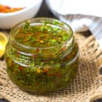 CHIMICHURRI SAUCE in glass jar with peppers in white bowl