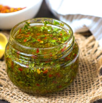 CHIMICHURRI SAUCE in glass jar with peppers in white bowl