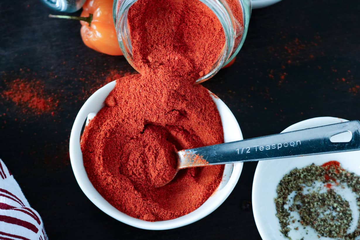 Cayenne pepper pouring into a white bowl