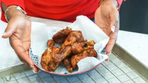 hand holding chicken on plate over rack
