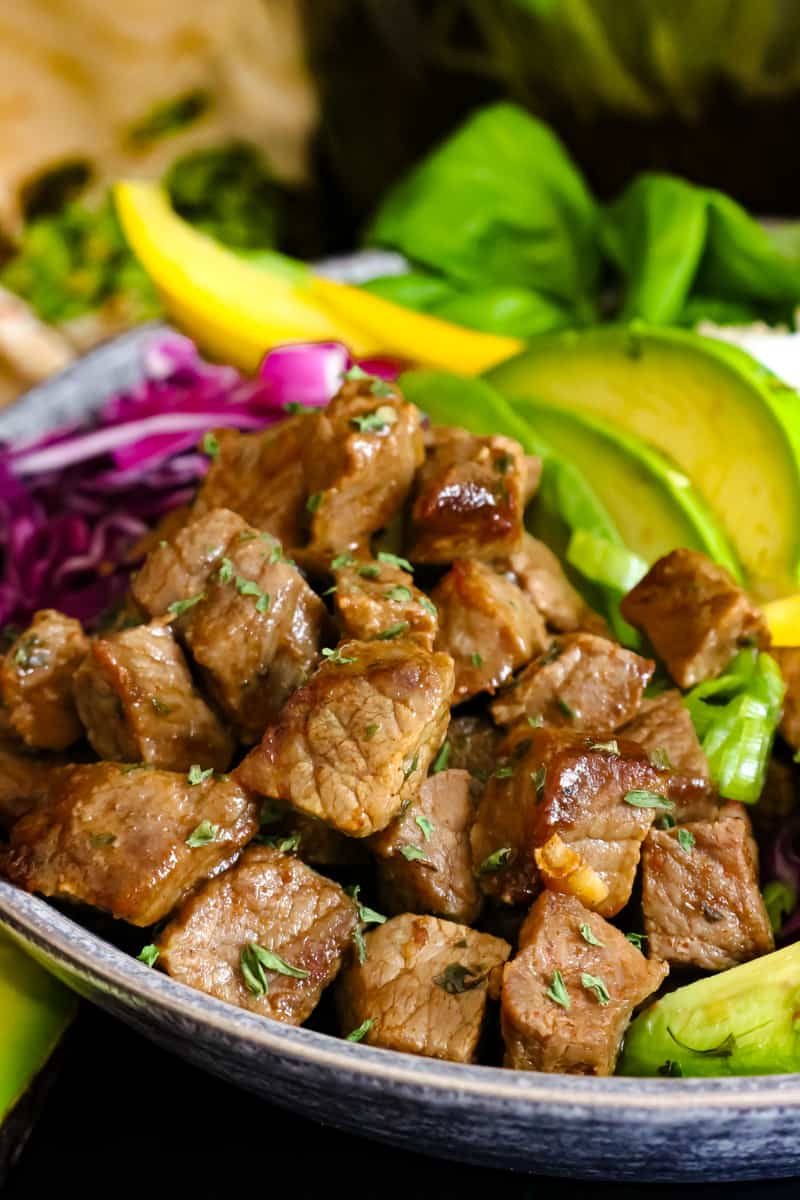 side view of steak bites, rice, veggies on gray plate