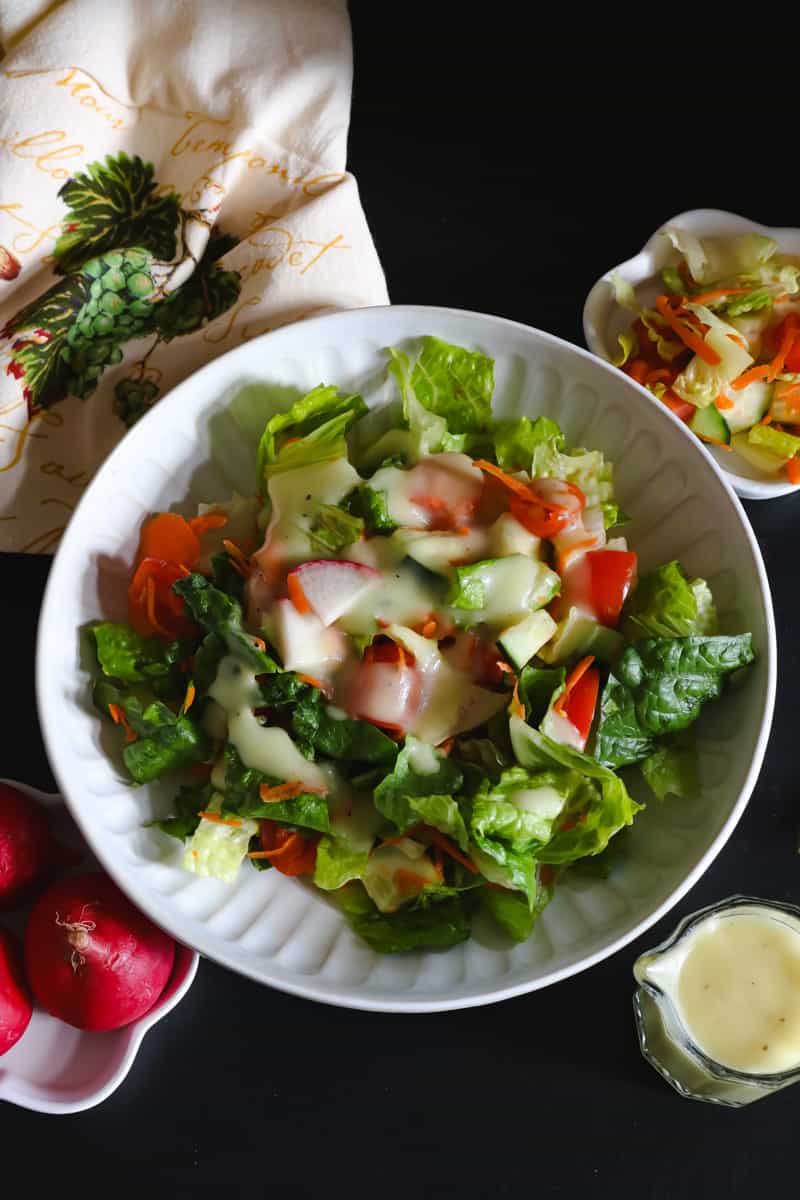 garden salad topped with dressing on blackboard