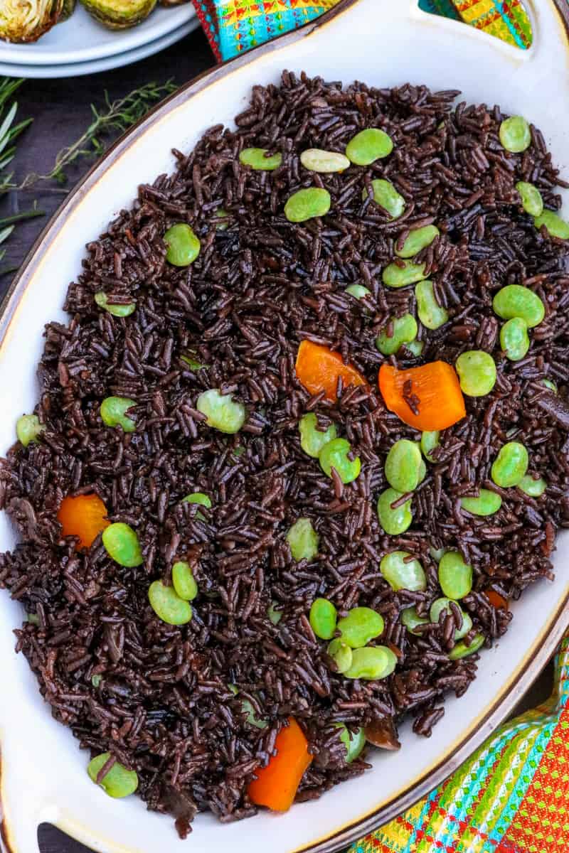 haitian black rice topped with green peas and orange bell peppers