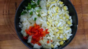 eggs, potatoes, green beens, red bell peppers, and onions in black bowl