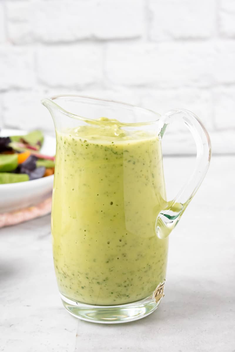 avocado Green Goddess Dressing in clear jar with salad on the back
