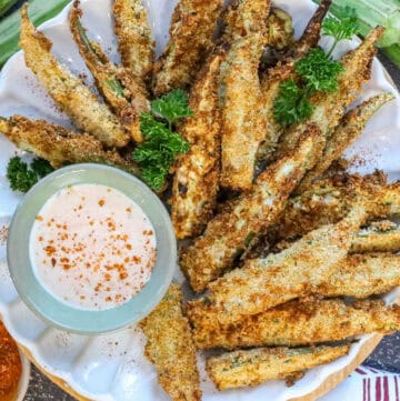 air fryer okra on white plate with fresh parsley and dipping sauce.