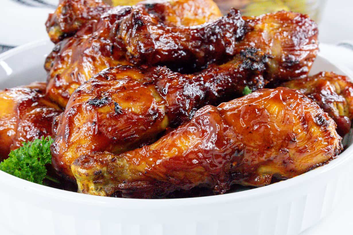 closeup view of cooked bbq air fryer drumsticks in white bowl with parsley