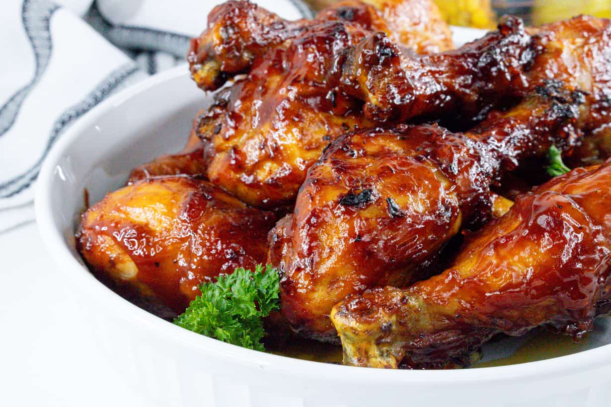 cooked bbq air fryer chicken legs in white bowl with parsley