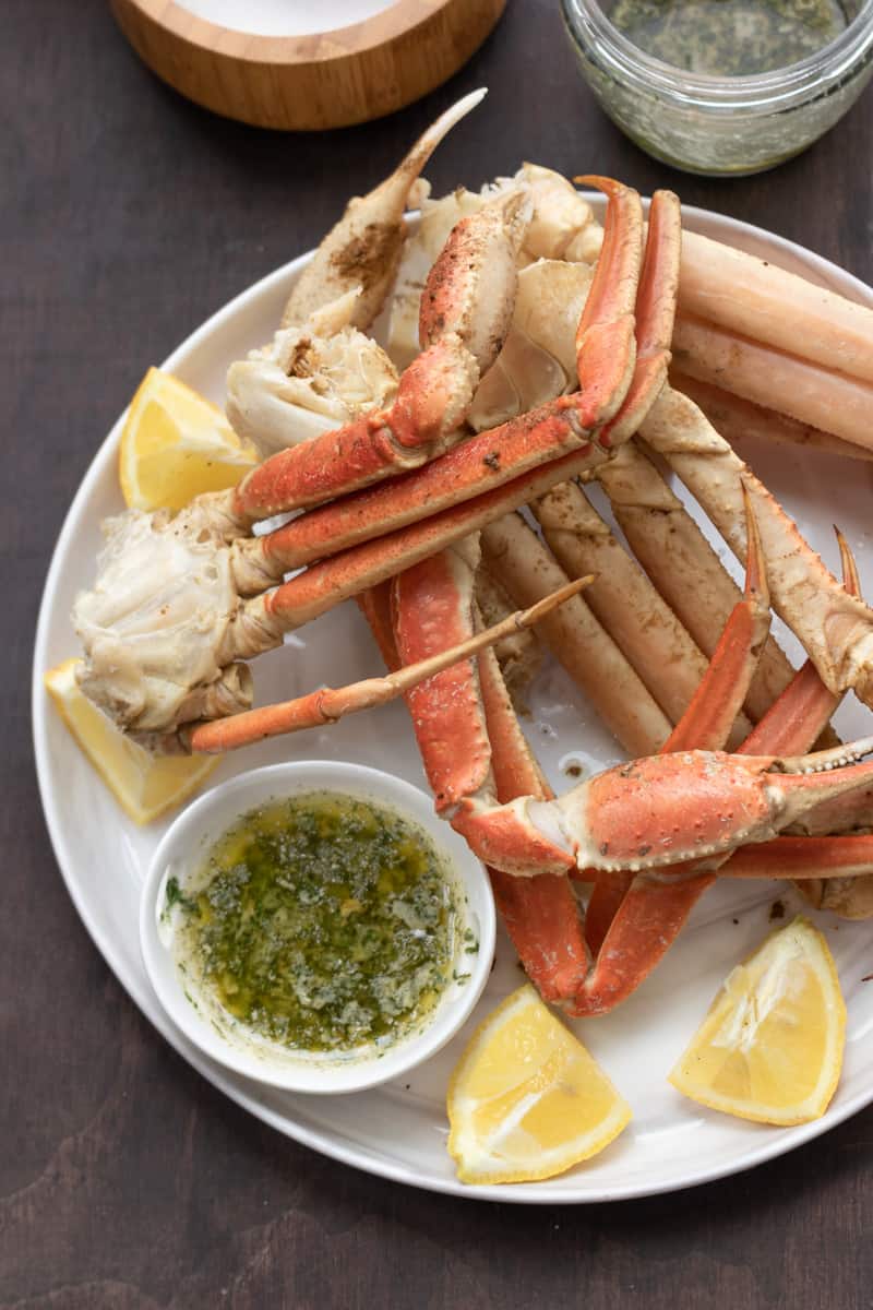 instant pot crab legs on white plate with lemon wedges and garlic butter sauce