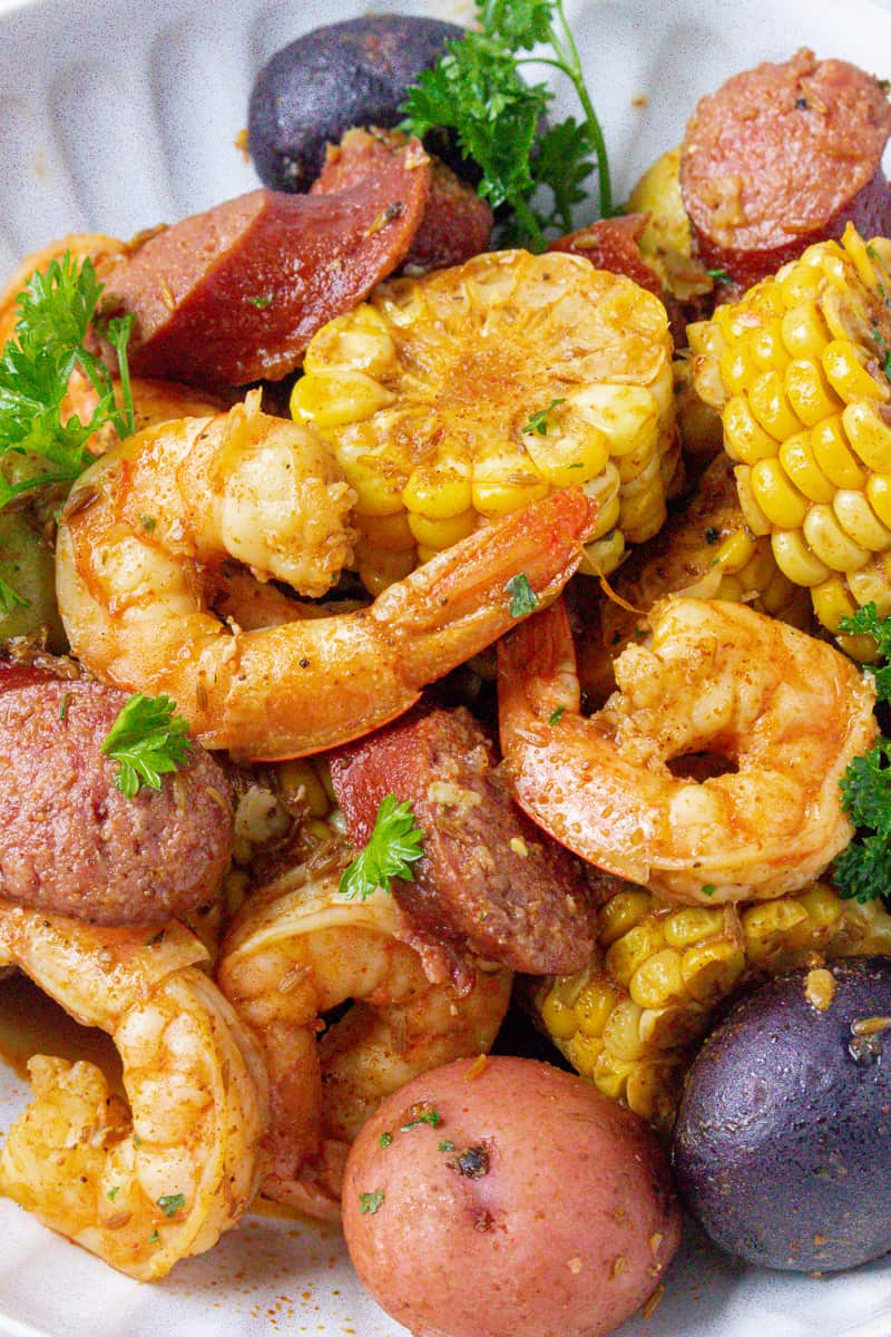 low country shrimp boil in white plate with parsley