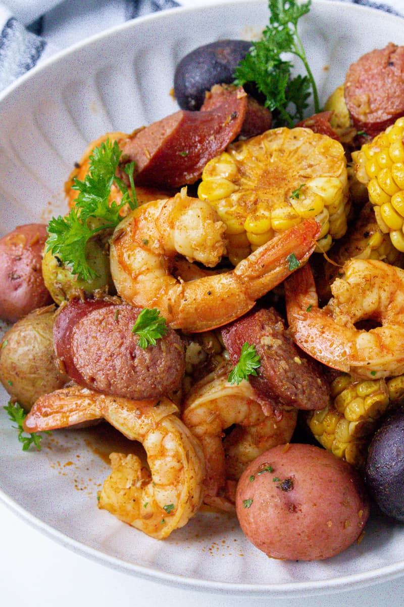 low country shrimp boil in white plate with parsley