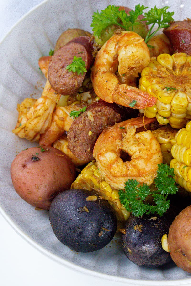 low country shrimp boil in white plate with parsley