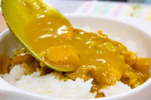 spoonful mango curry in spoon over rice