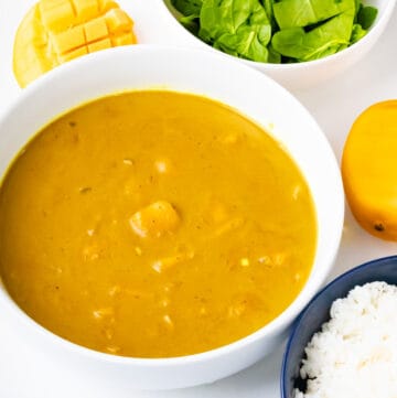 horizontal view of mango curry with spinach and mango and rice on white bowl