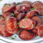 cooked air fryer sausage on white plate topped with fresh parsley flakes