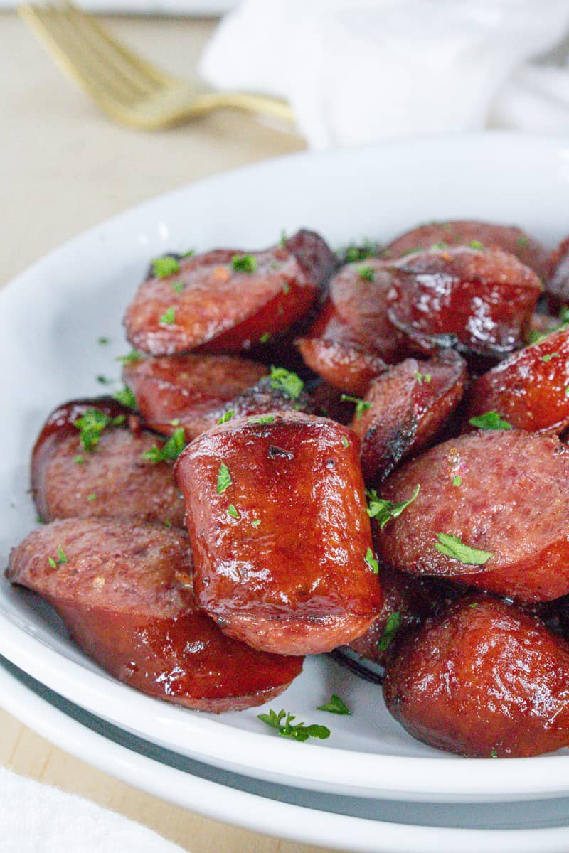 cooked air fryer sausage on white plate topped with fresh parsley flakes