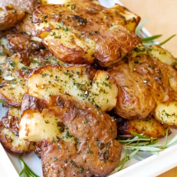 potatoes on board with rosemary in white tray