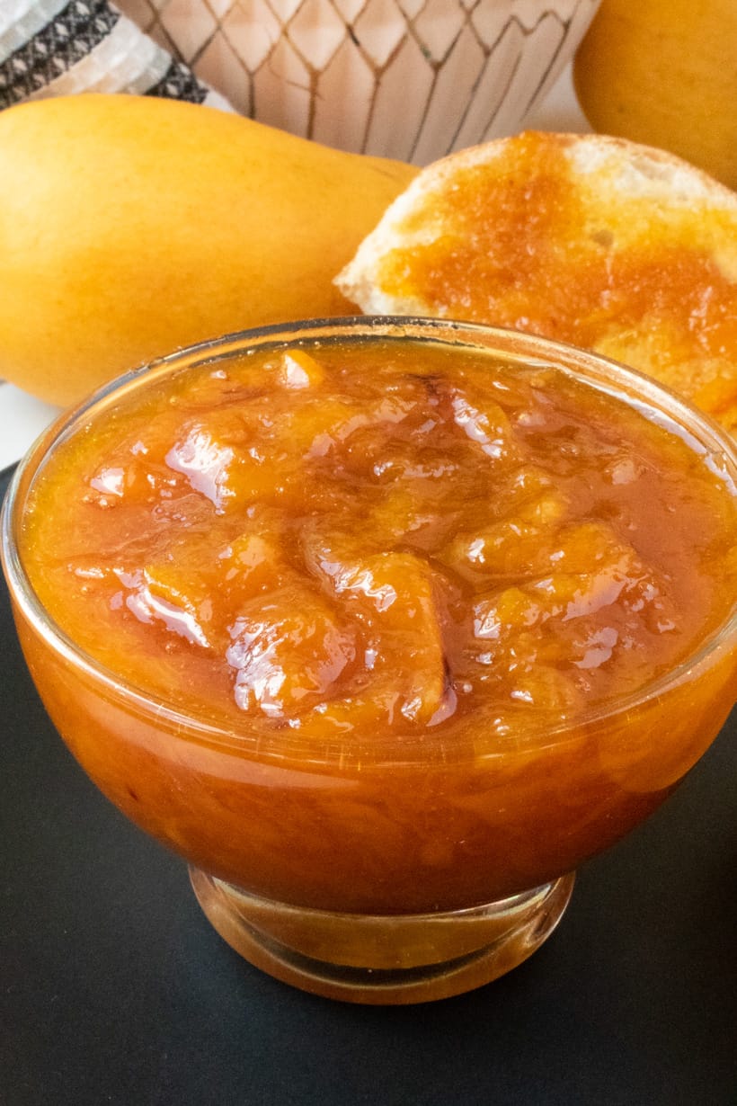 mango jam in glass jar on black plate