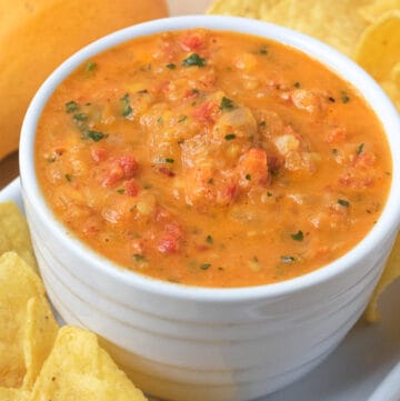 Mango salsa in white bowl with chips and mango