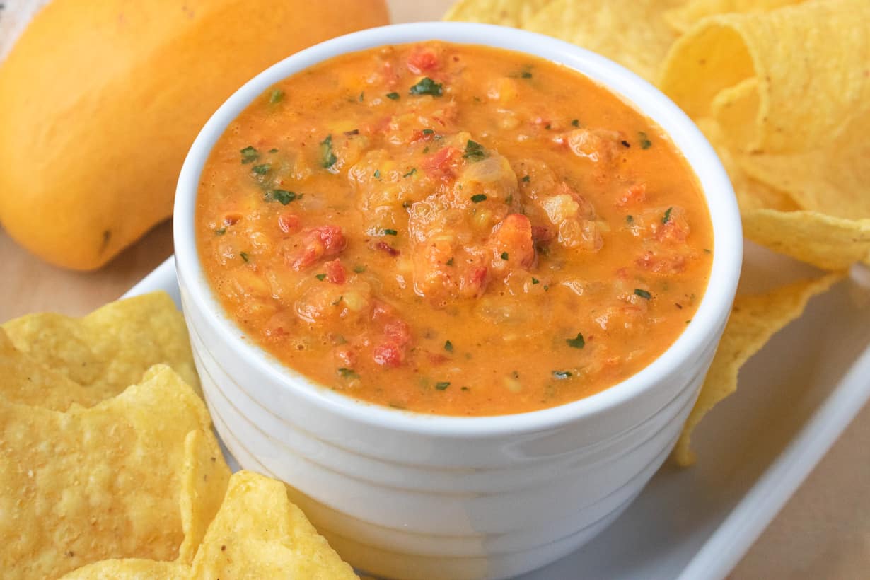 Mango salsa in white bowl with chips and mango