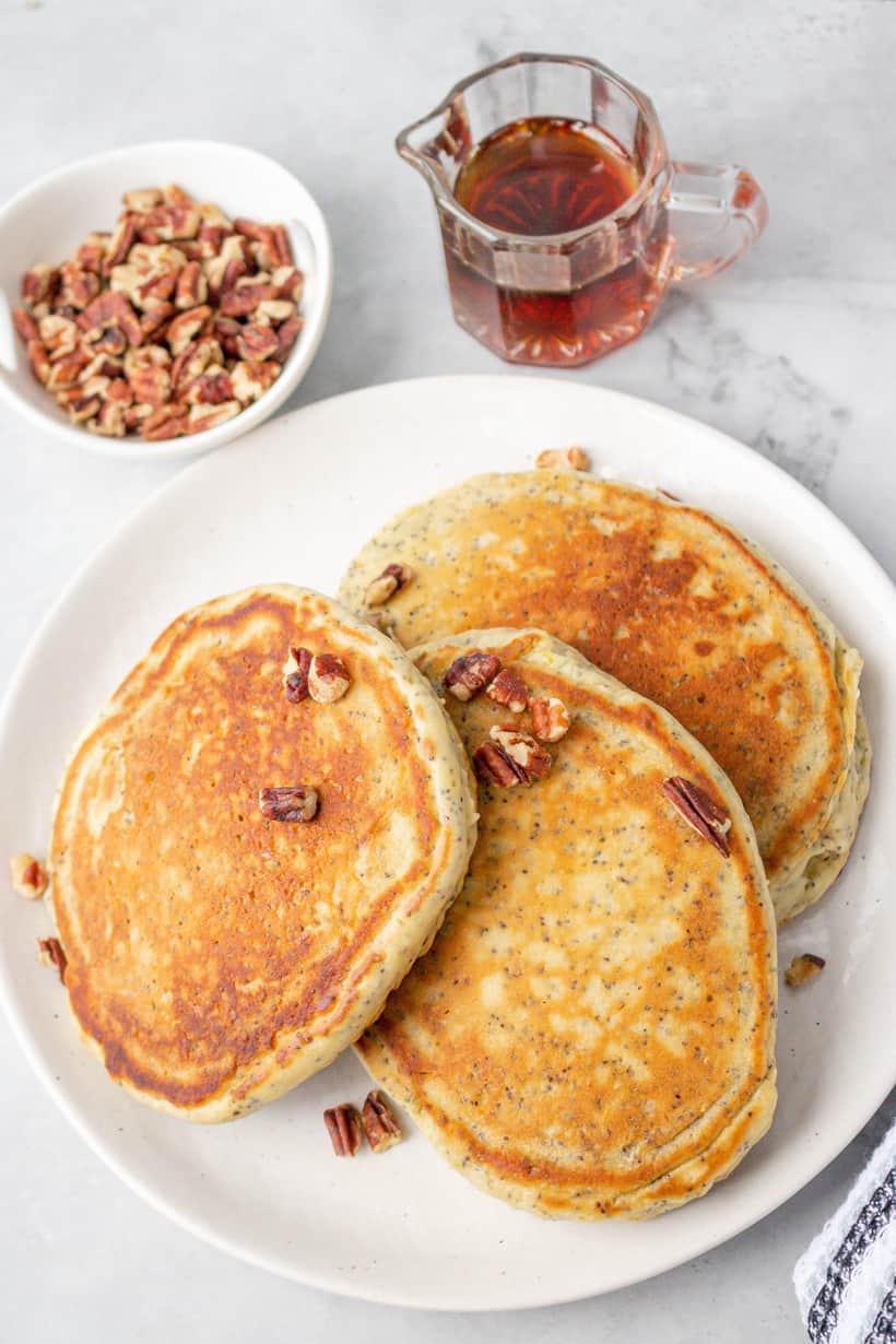 pancakes, syrup, and nuts on gray board in white plate