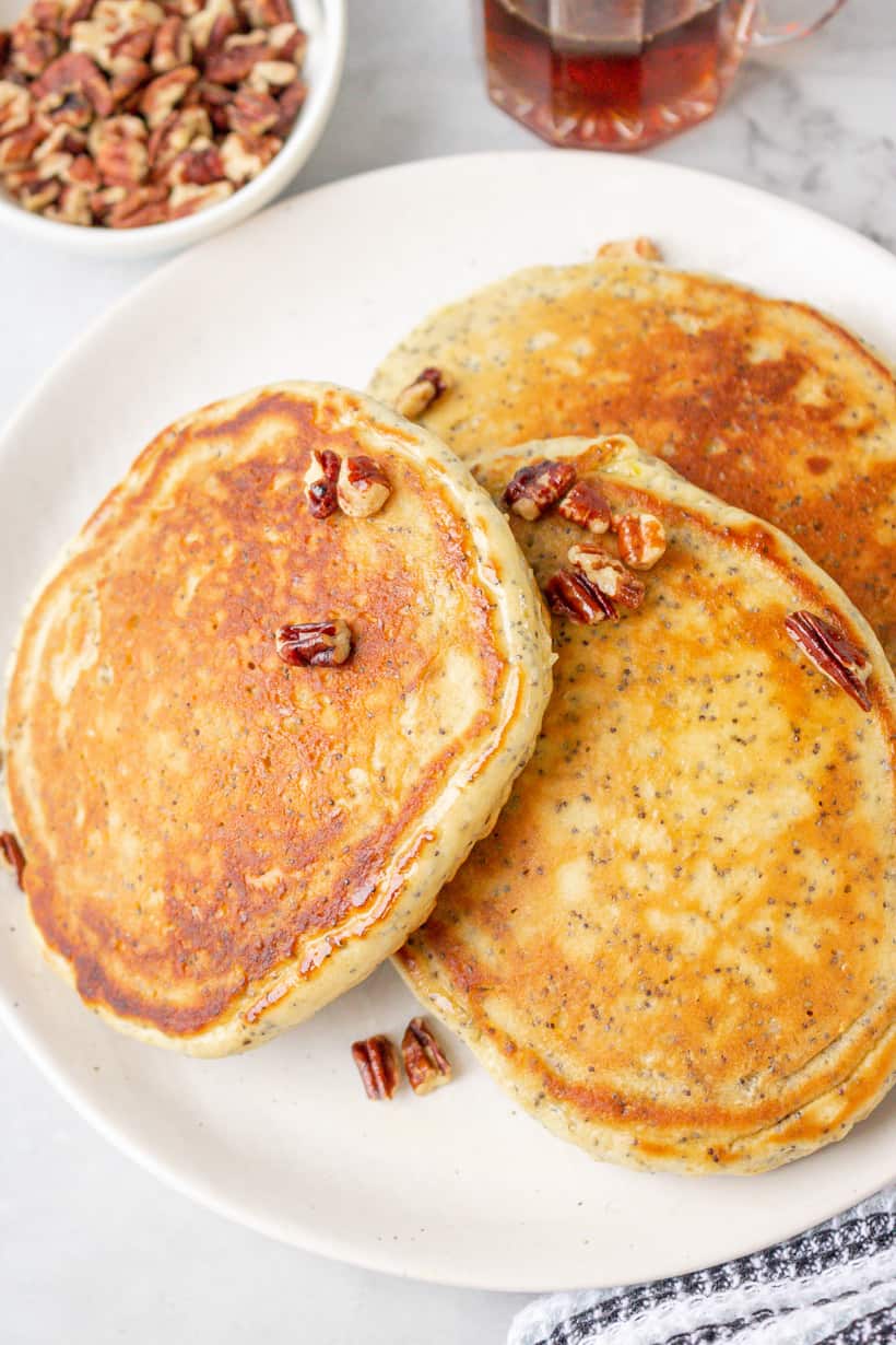 stacks of pancakes in plate topped with pecans