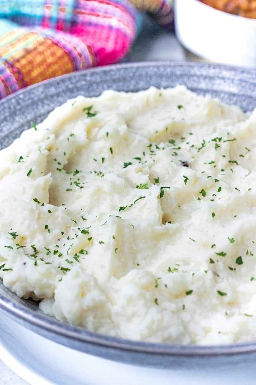 Mashed potatoes in gray bowl topped with herbs