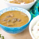 gravy in blue bowl with mashed potatoes on the side