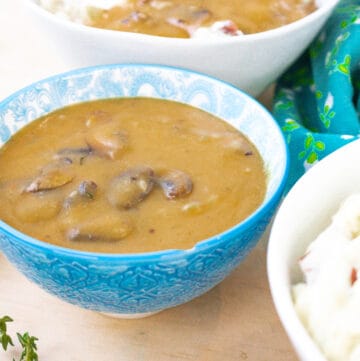 gravy in blue bowl with mashed potatoes on the side