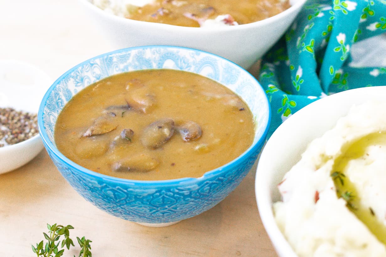 gravy in blue bowl with mashed potatoes on the side