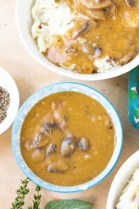 Vegan Mushroom Gravy on brown cutting board with mashed potatoes - Savory Thoughts