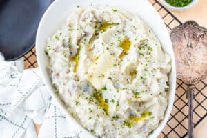 mashed potatoes in white bowl with herb and butter