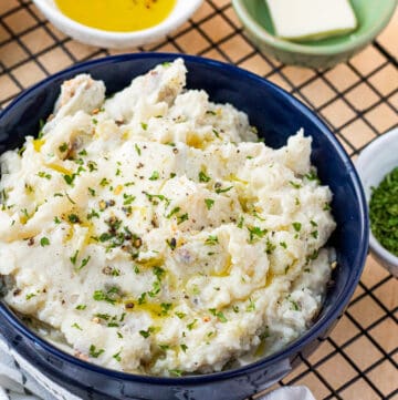mashed potatoes in blue bowl with herbs and butter