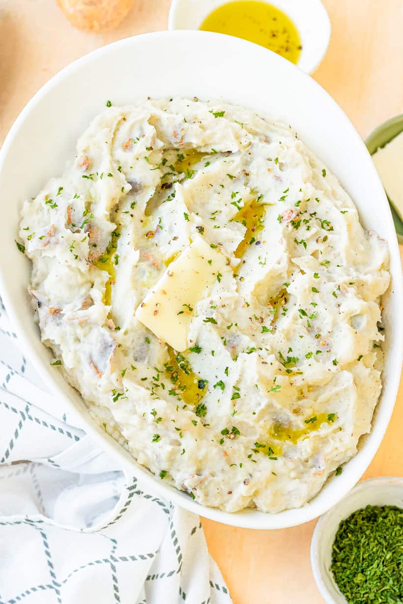 mashed potatoes in white bowl with herb and butter