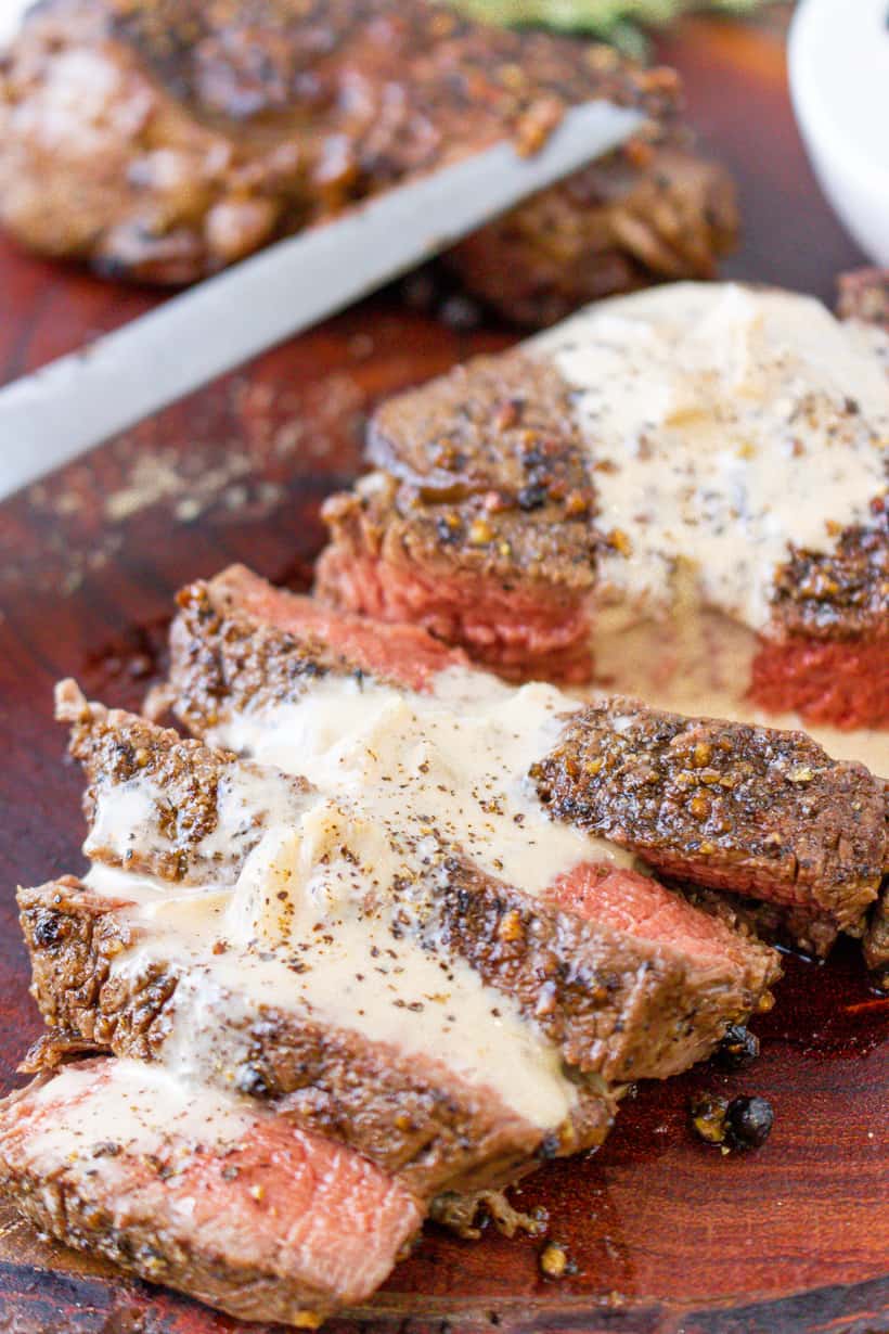 steak topped with cognac creamy sauce on wooden board