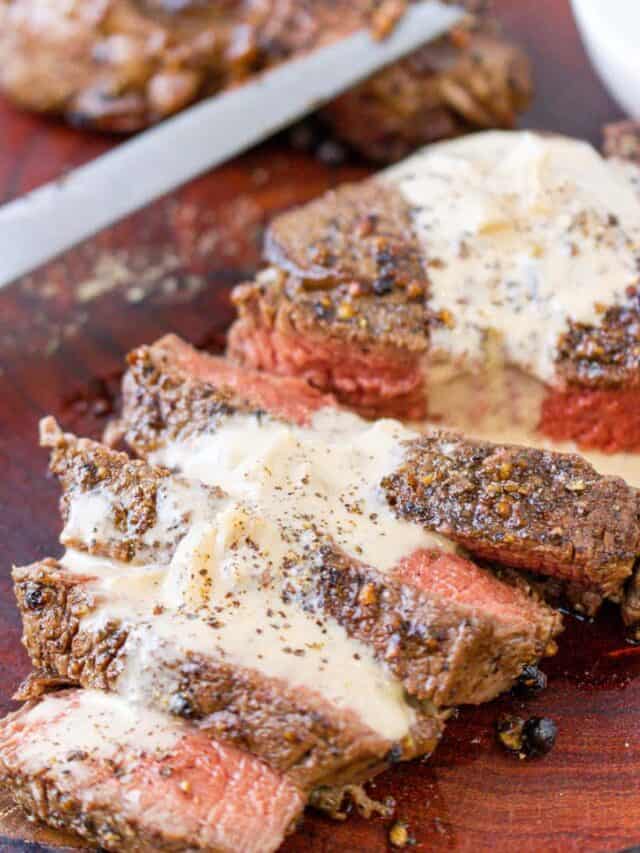 steak topped with cognac creamy sauce on wooden board