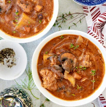 veal stew in white bowl with herbs