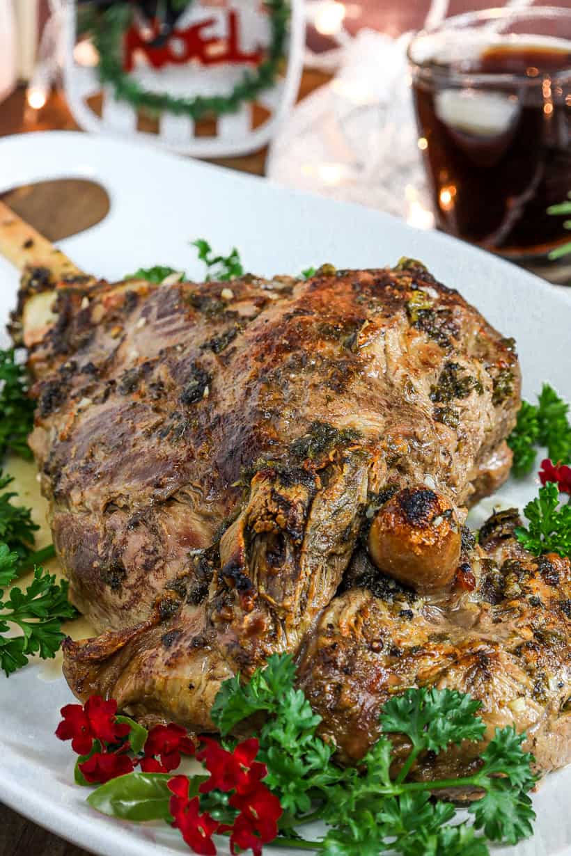 bone in leg of lamb on white plate with herbs