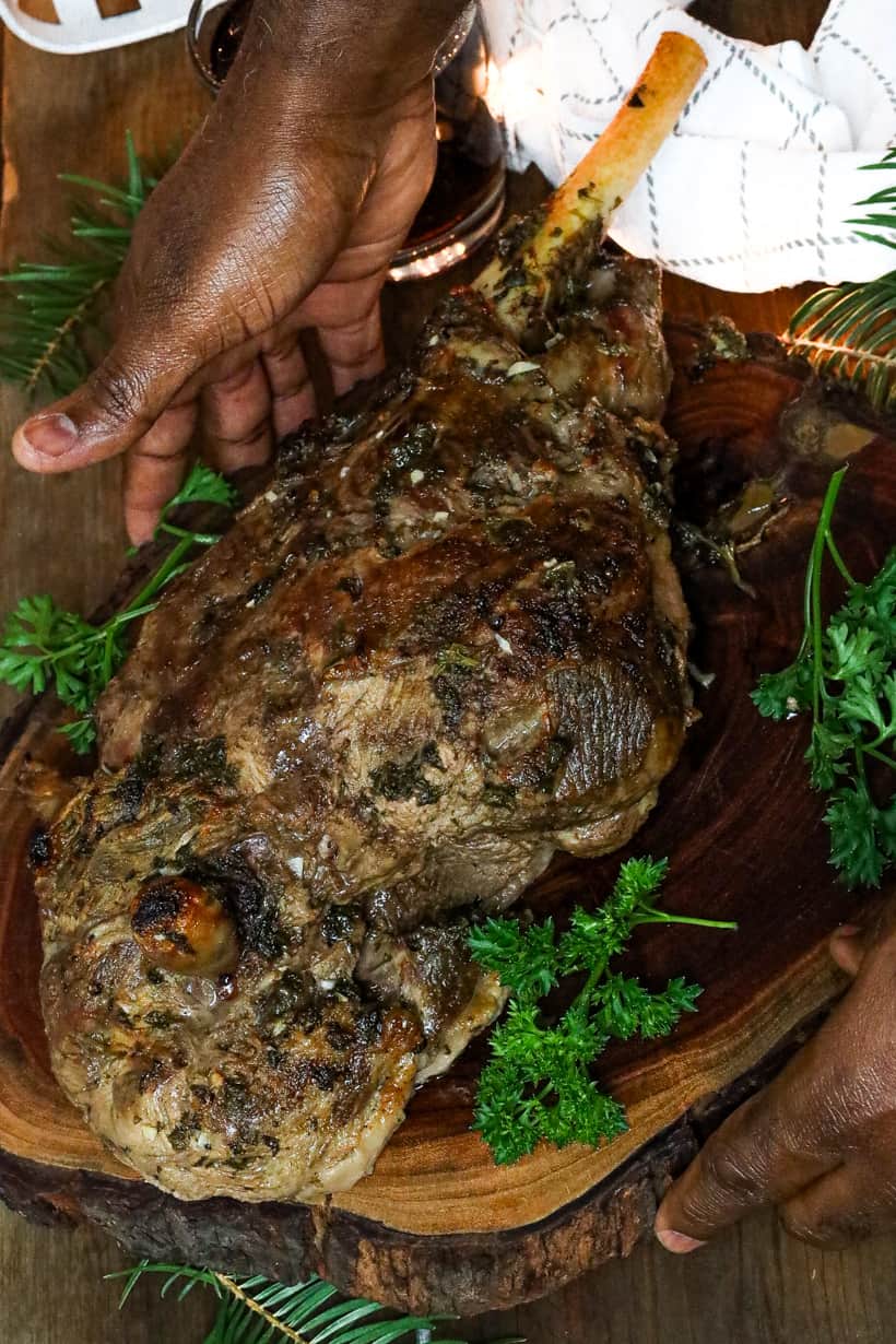 Leg of lamb on wooden board with fresh parsley