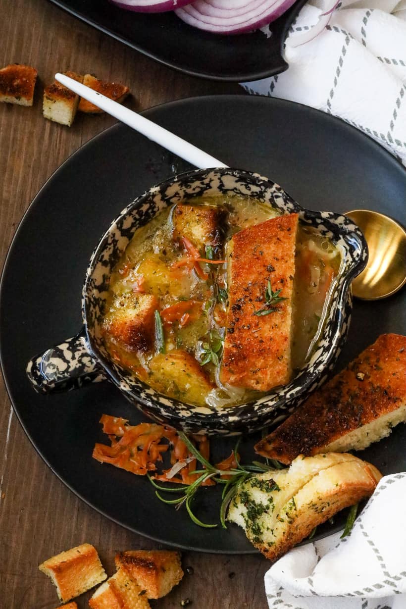 French onion soup in bowl on black plate with bread