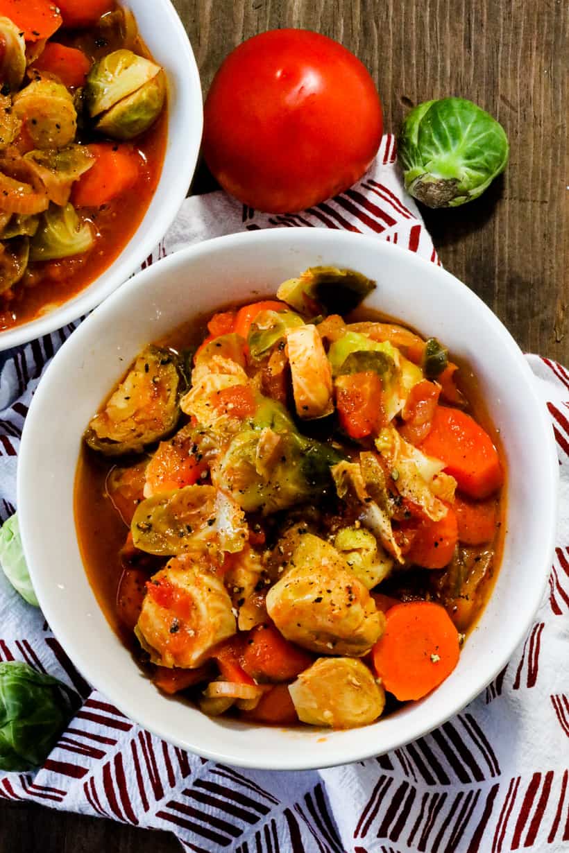 Brussels Sprouts And Carrots stew in bowl over wooden background